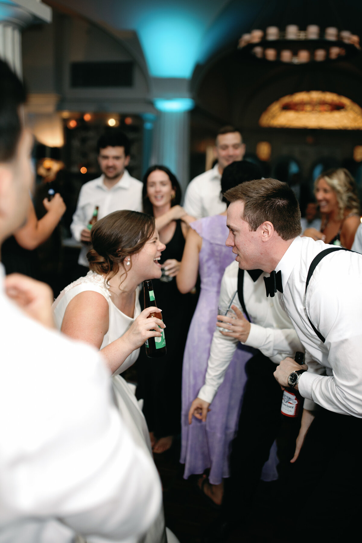 Bride in satin gown laughing with guests while dancing at DC hotel wedding reception.