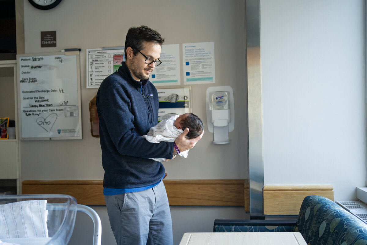 Dad holding newborn baby boy in hospital room