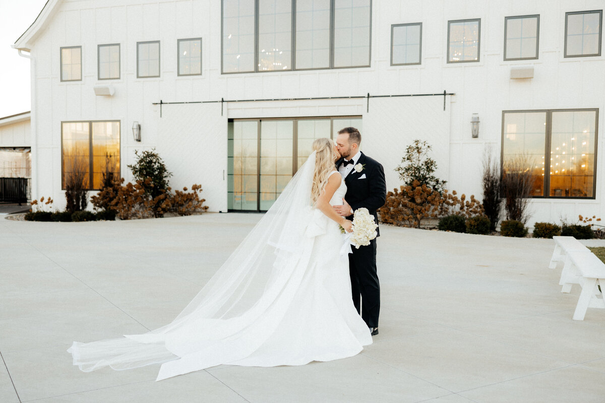 The bride and groom standing in front of the white barn wedding venue.