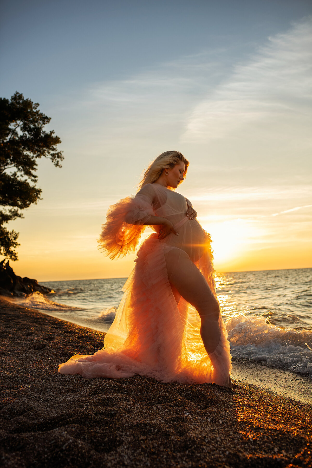 sunrays in pregnant belly during maternity photoshoot in Lake Michigan