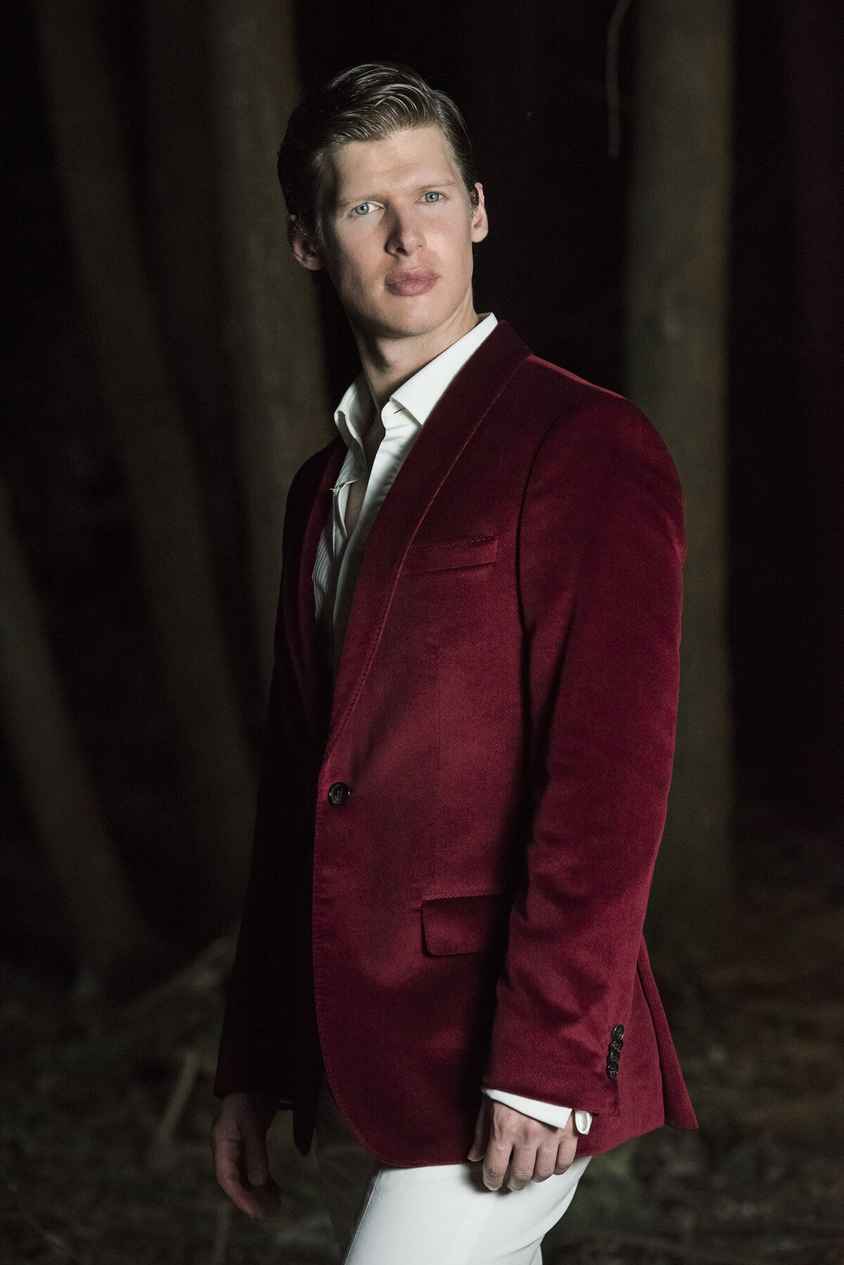 A person in a red suit jacket looking off to the side