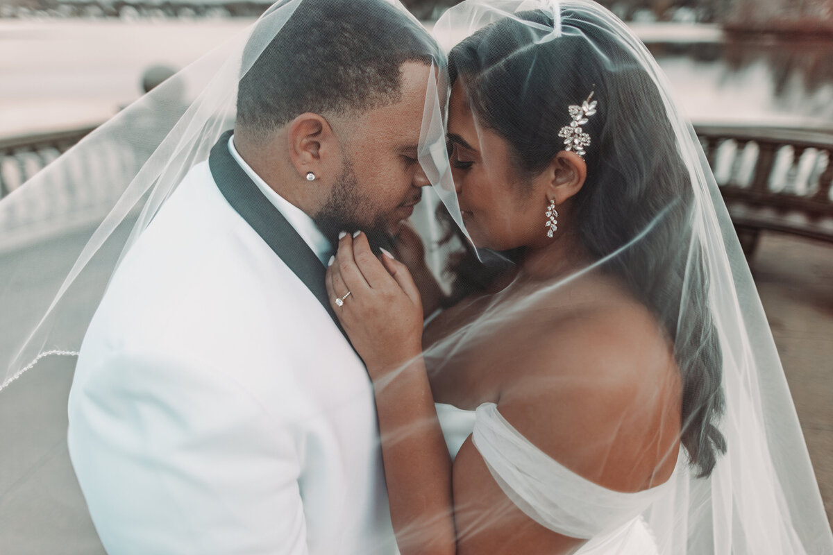 Bride and groom closing their eyes with bride's veil over them