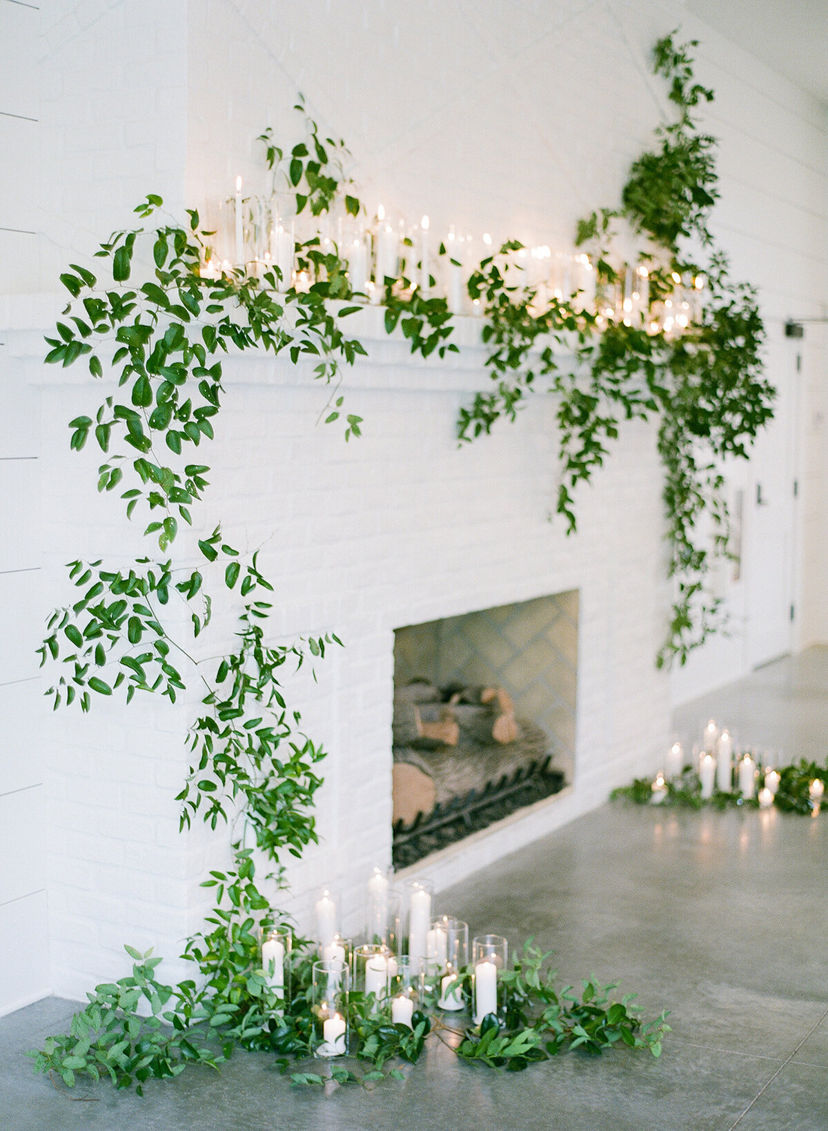 Lush floral fireplace mantle installation with all white candles