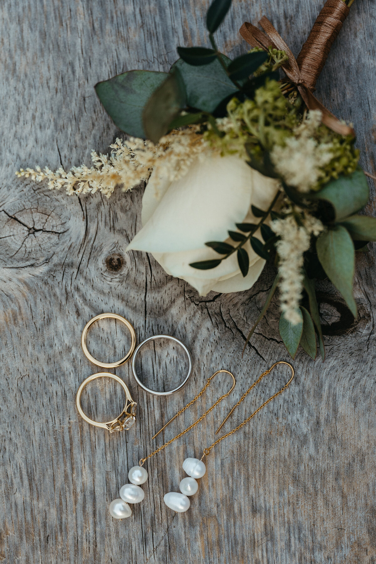Wedding rings placed on a rose with greenery accents