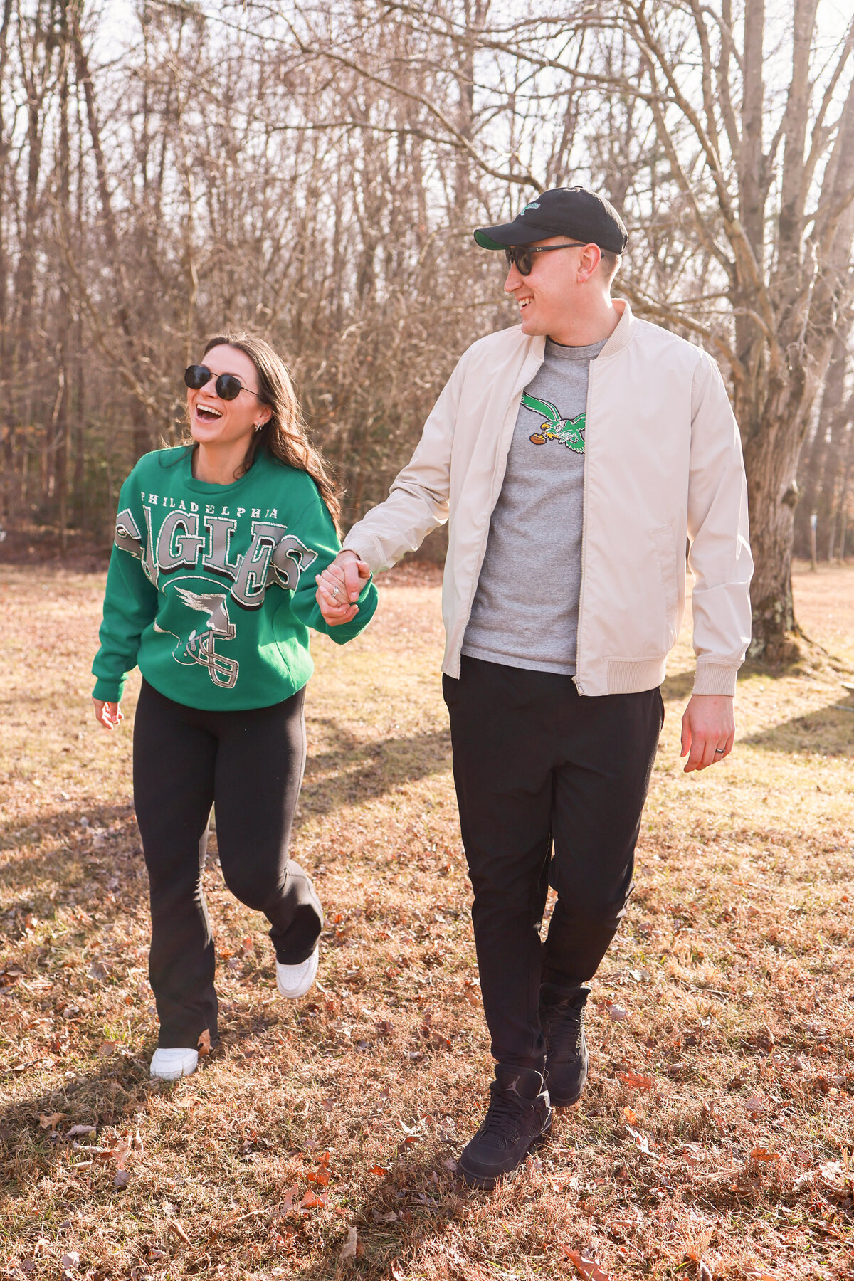 husband and wife wearing philadelphia eagles football sweaters and sunglasses and laughing