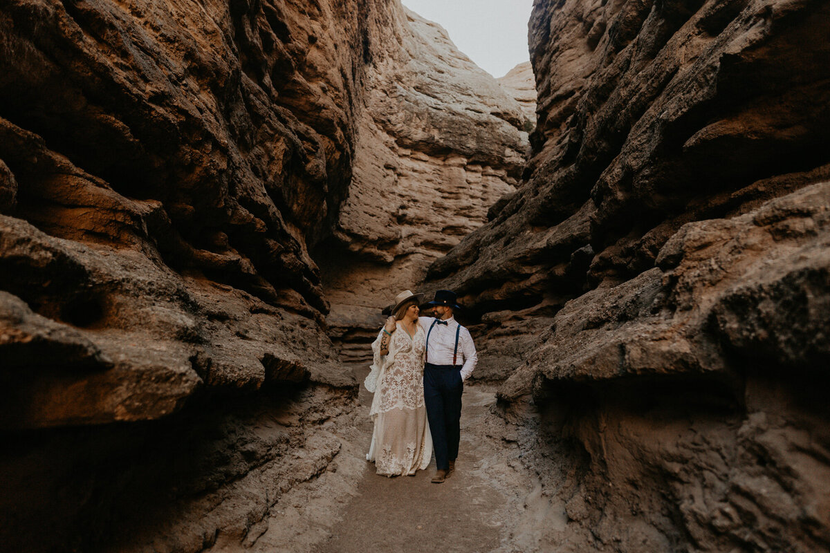 bride and groom walking together in a slot canyon