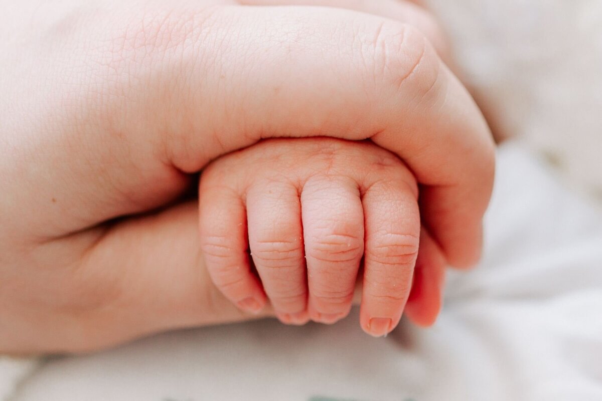 Mother holds newborn baby's hand