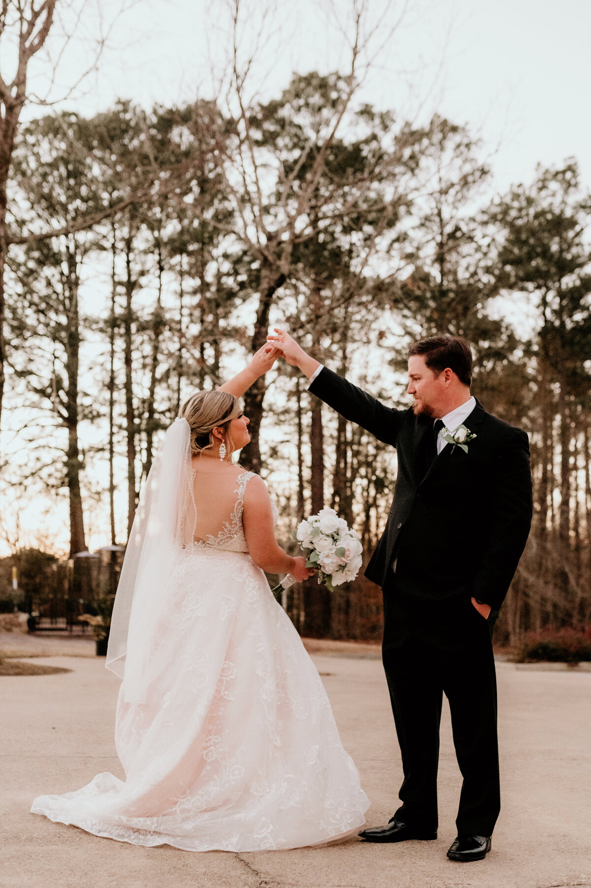 Little Rock wedding photographer photographs bride and groom dancing together outside in the woods as the sun sets