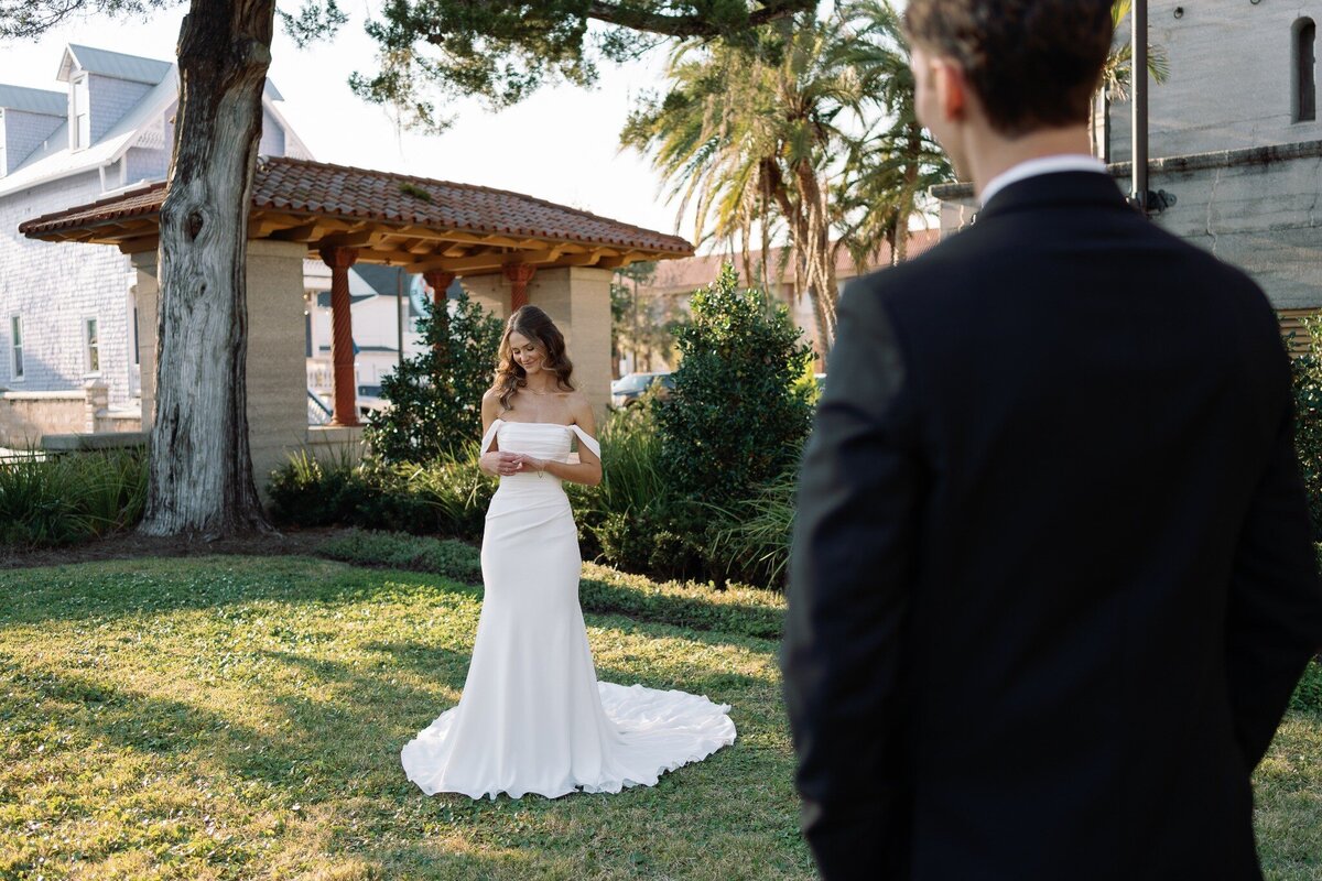 Bride and Groom standing in greenery looking at their rings by east coast photographer