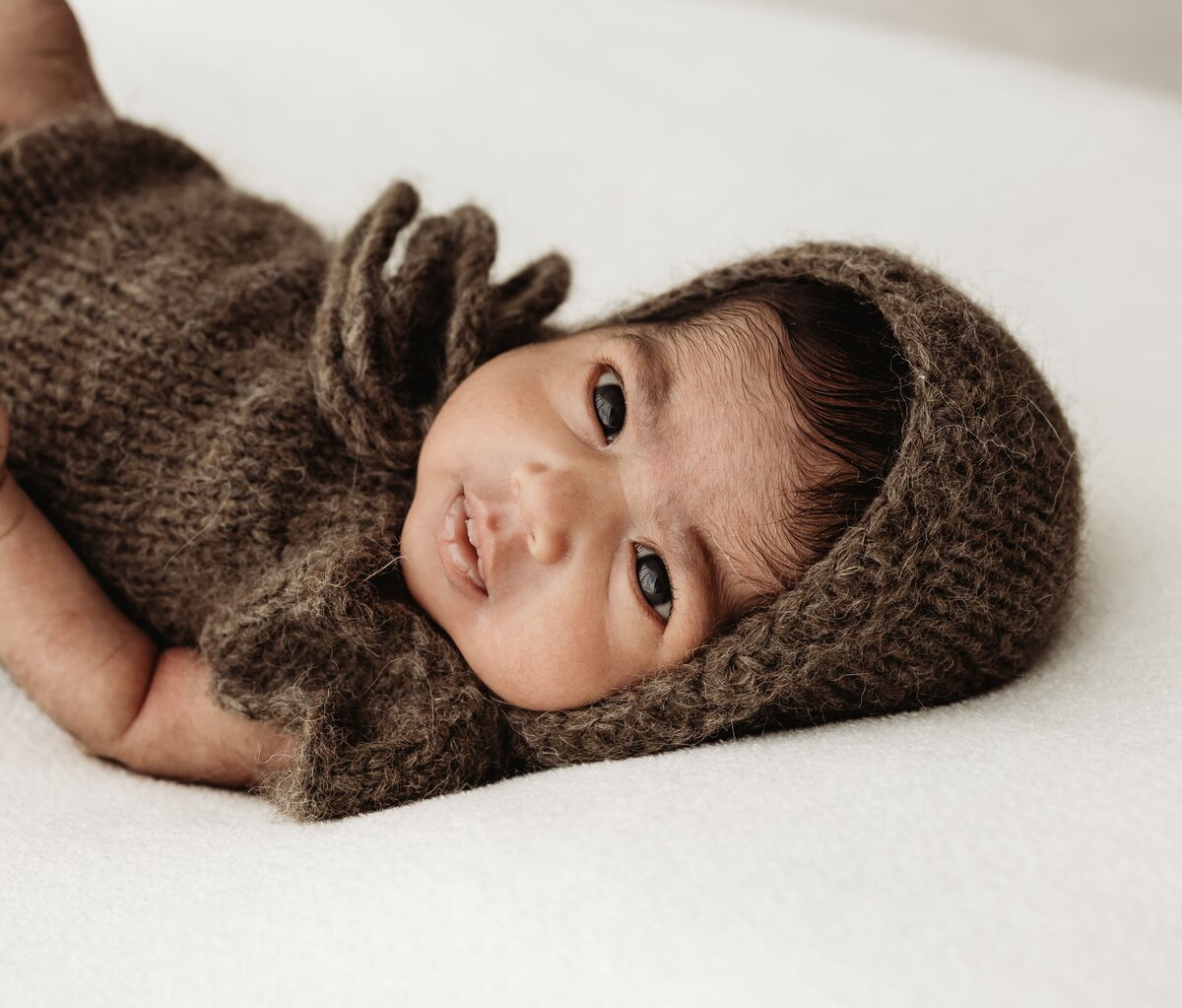 A young girl in a brown dress gently touches the bark of a large tree, as the setting sun casts a warm golden light in the park. Children's photography by Ruaa Hamdan