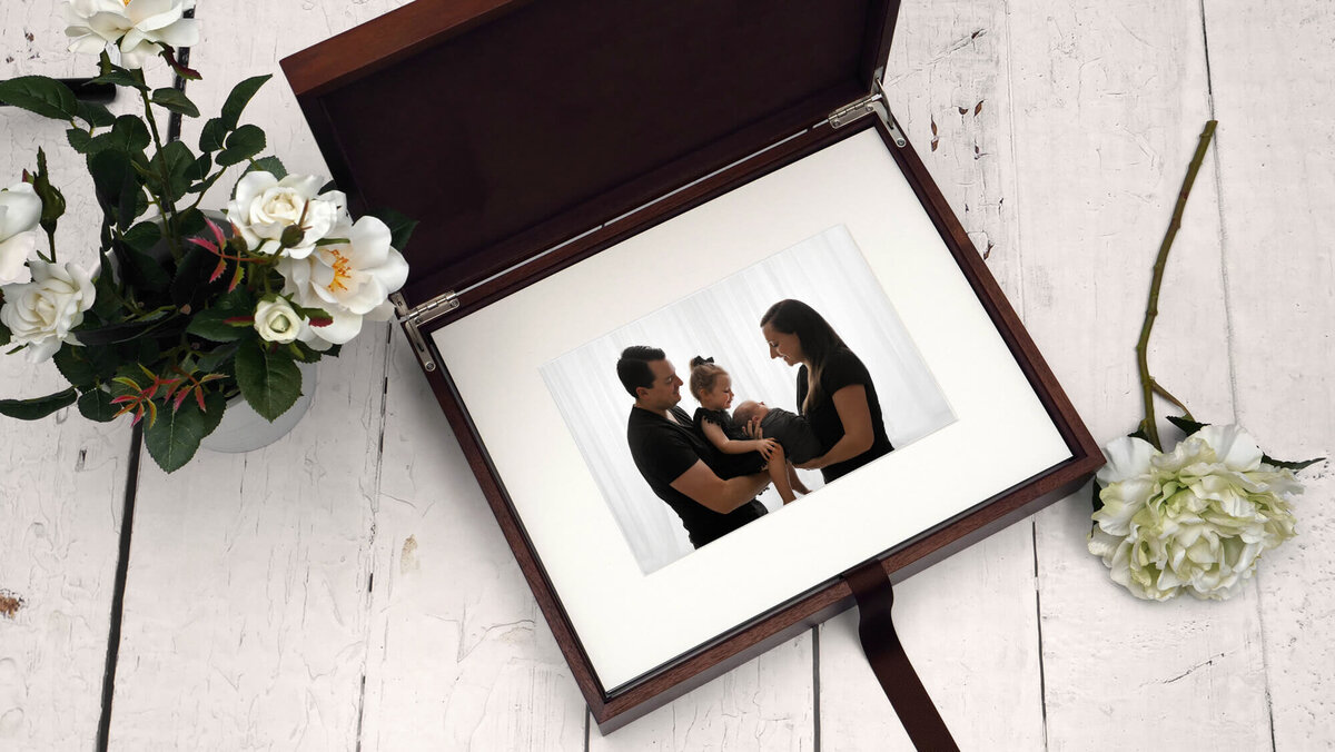 photography luxury wooden keepsake box containg matted newborn family print with flowers next to it