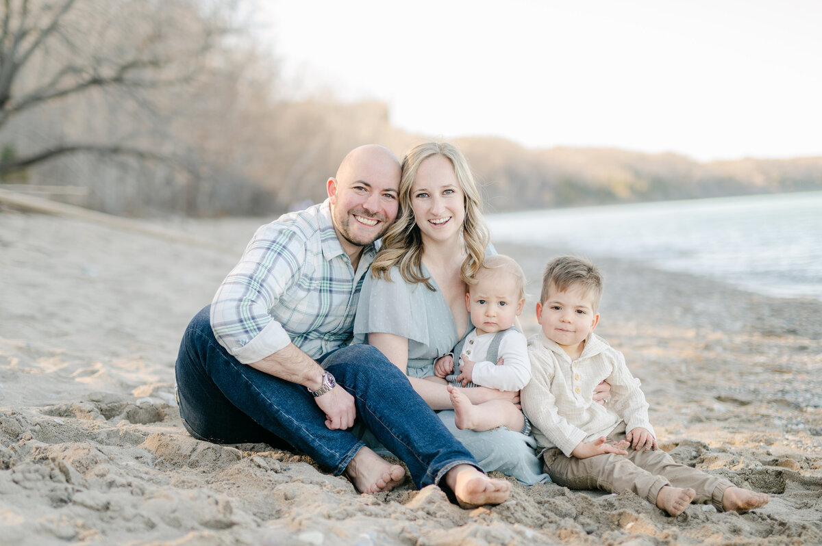 A family consisting of a mother and father and two boys are all smiling at the camera for a Milwaukee family photo session