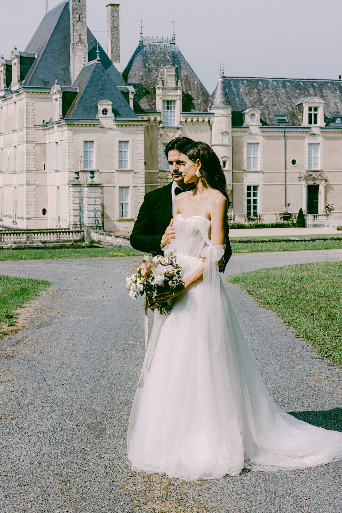 Candid photo of a husband and wife on their wedding day standing in front of chateau de jalesnes in France