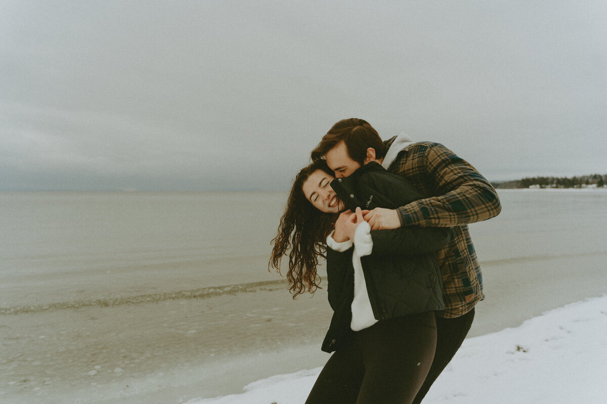 heartfelt winter engagement photo at the icy snowy beach