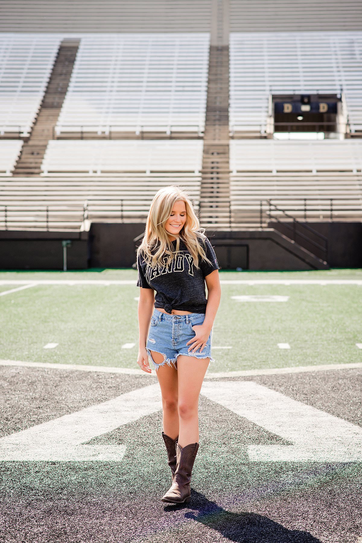 Vanderbilt Senior wearing a school shirt and jean skirt standing on football field