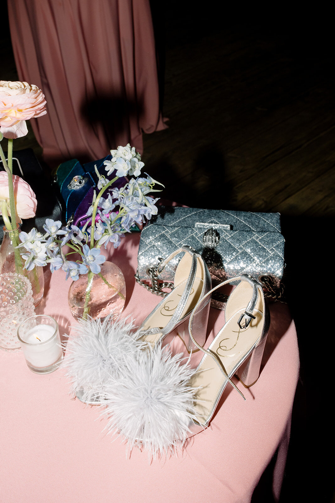 Flash photo of wedding reception table with a silver purse and feather heels
