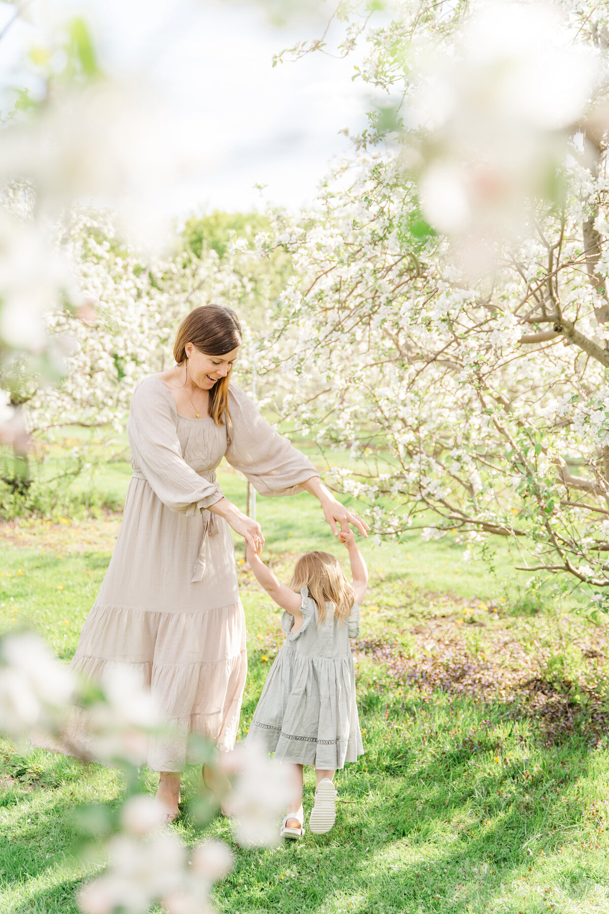 a mother dances with her daughter in a field of cherry blossom trees