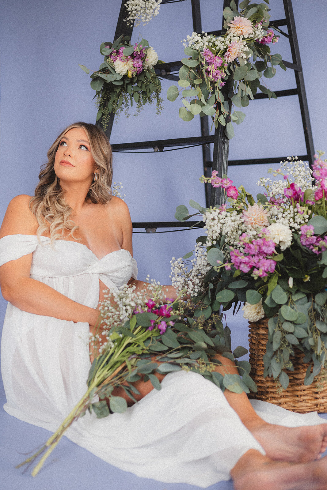 A pregnant woman poses surrounded by flowers