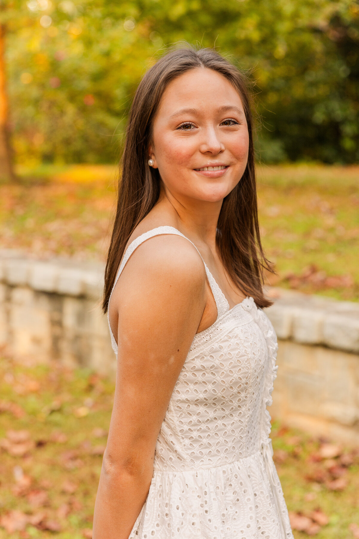 teenage girl wearing a white dress and looking over her shoulder in an Atlanta park during portrait photoshot