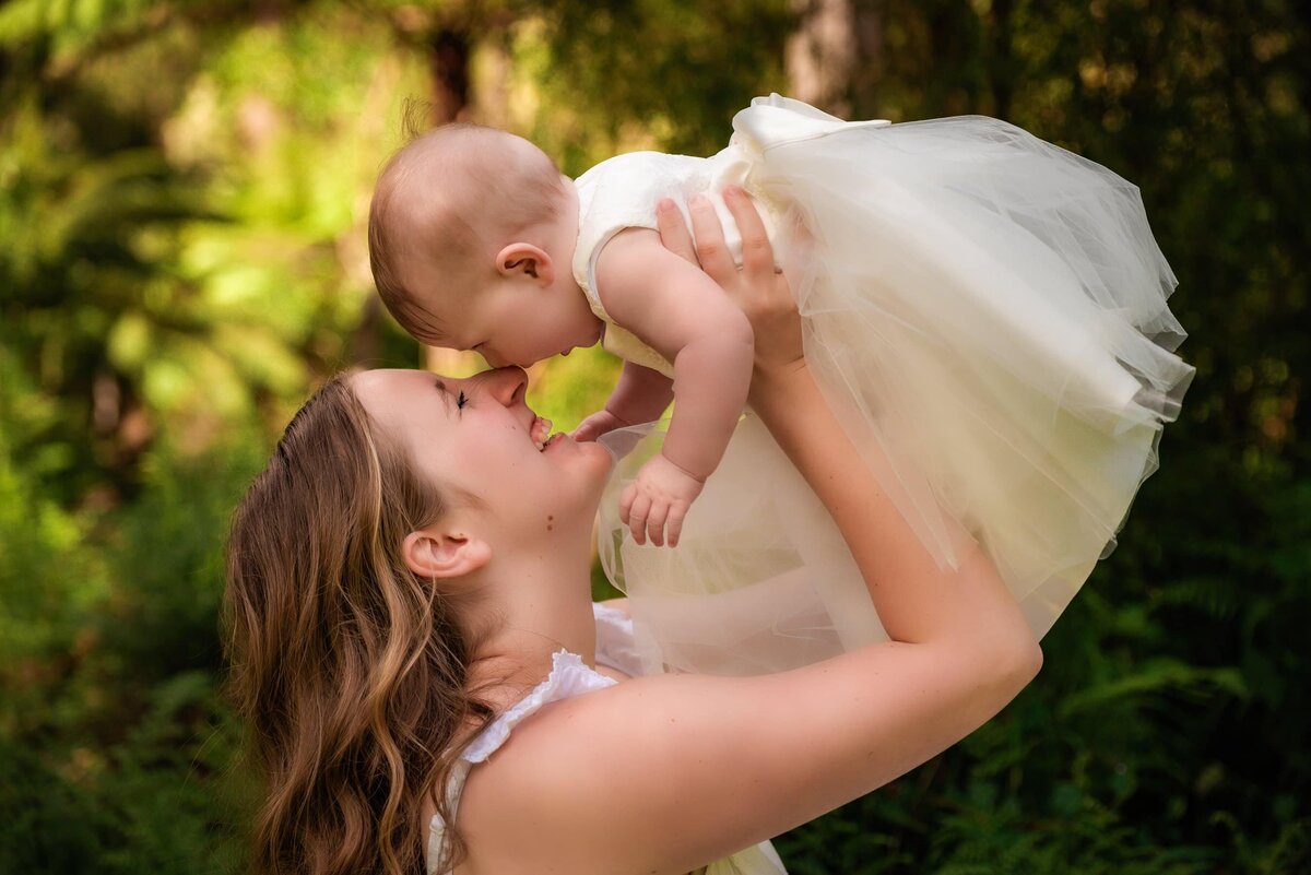 mother playing with baby daughter in foreest