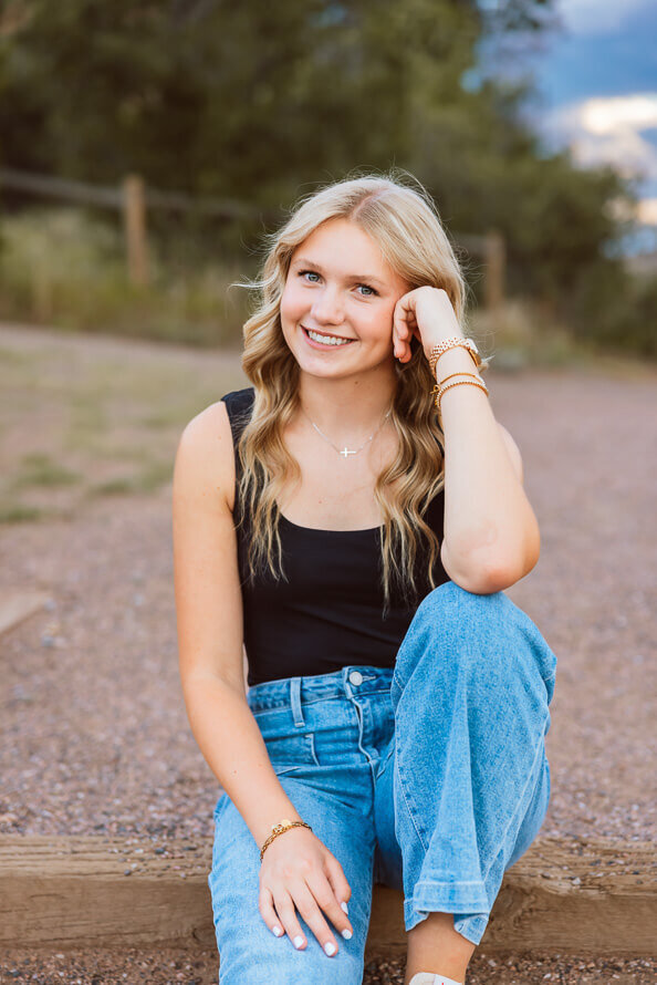 Senior girl puts elbow on knee while posing for her senior photo.