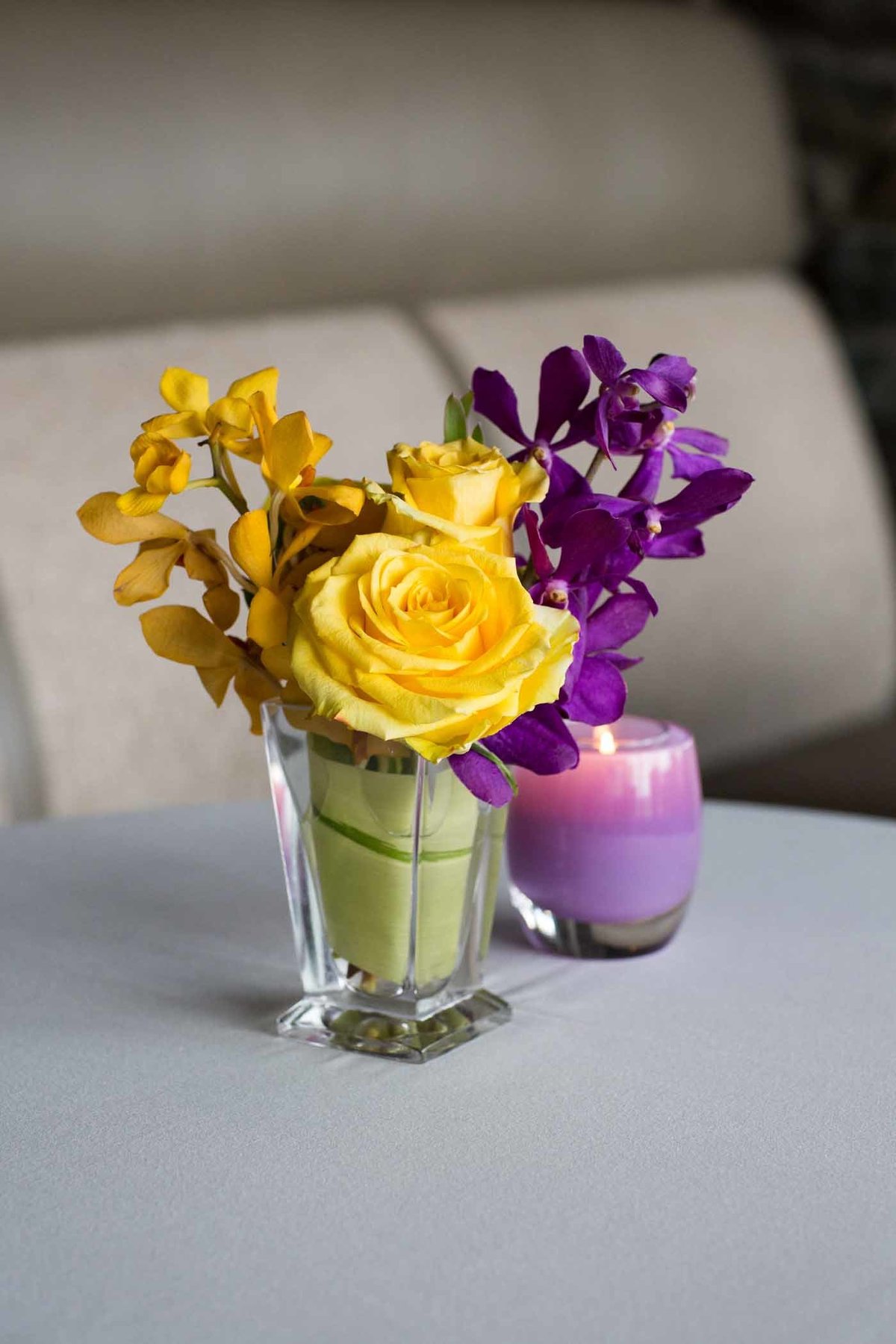 flower centerpiece with yellow rose and purple orchids with purple glassybaby candle