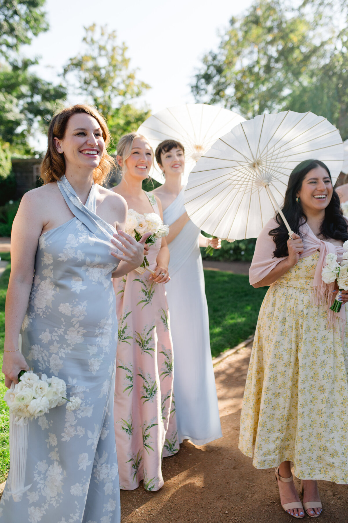 Close-up of bridesmaids laughing, with one in a floral dress and another in a yellow dress.
