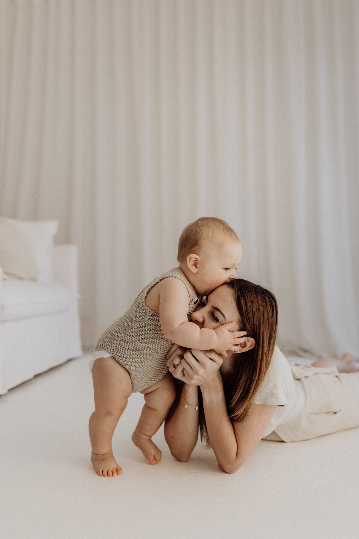A baby laughing and playing with his mum during a milestone photoshoot in canterbury in the studio