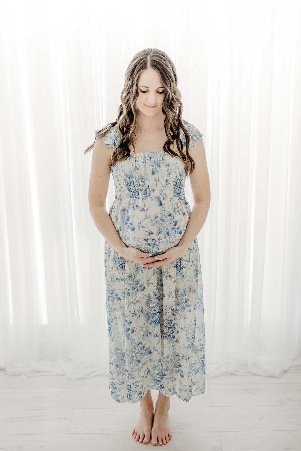 Mom in blue dress backlit maternity session