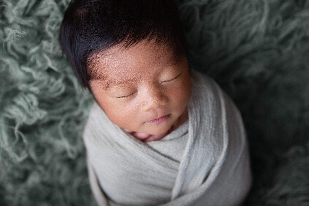 Blue wrapped studio newborn pose on a blue flokati