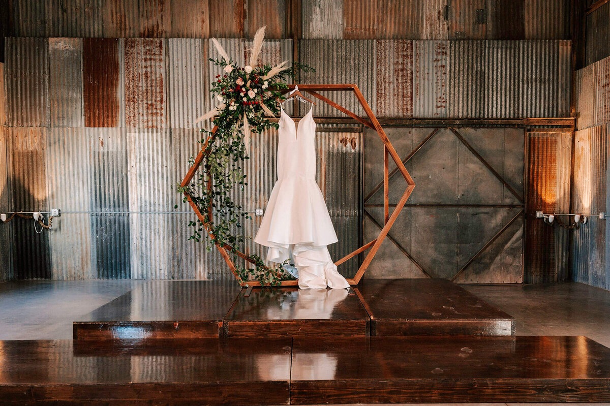 Bride's wedding dress hanging from the octagon wedding arch at kitalou gin wedding venue