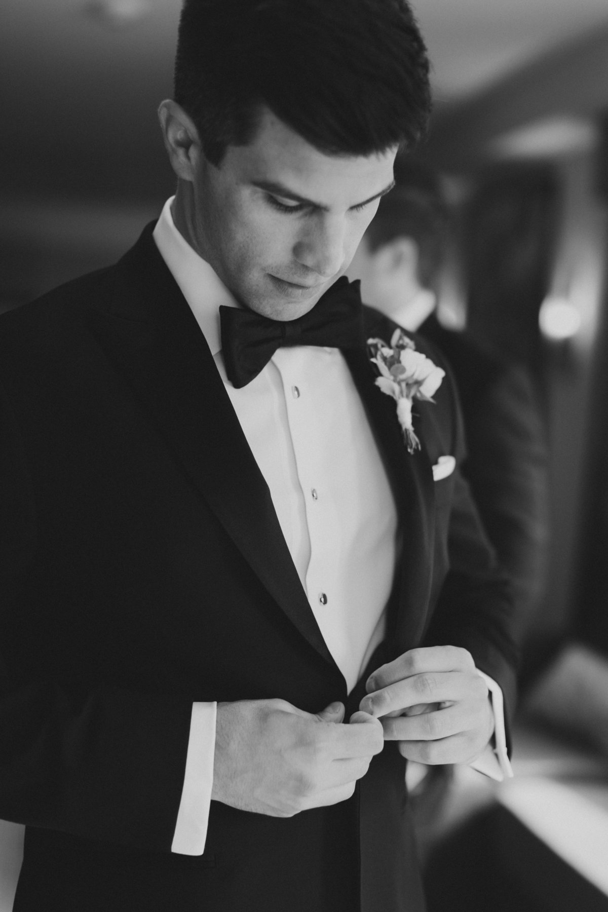 groom buttoning buttons on tuxedo on wedding day