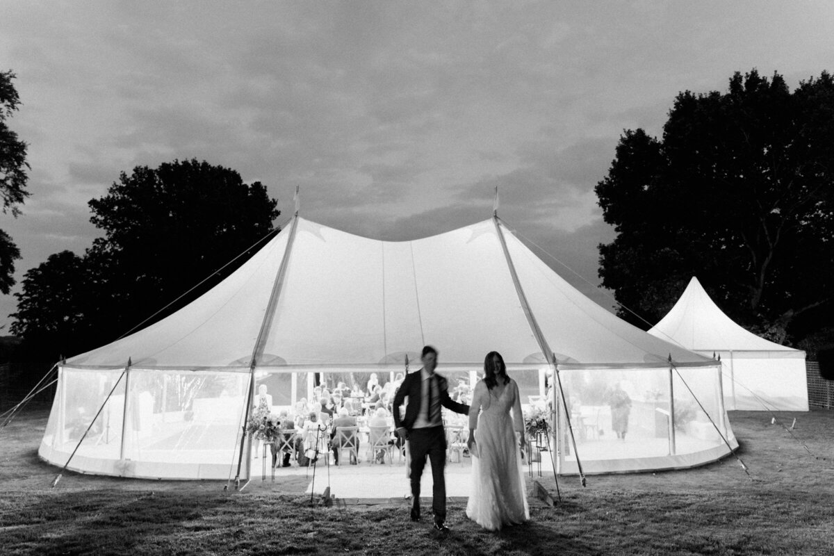 bride and groom in front of marquee at summer wedding captured on black and white