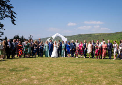 A large group of wedding guests congregating for a wedding photo.