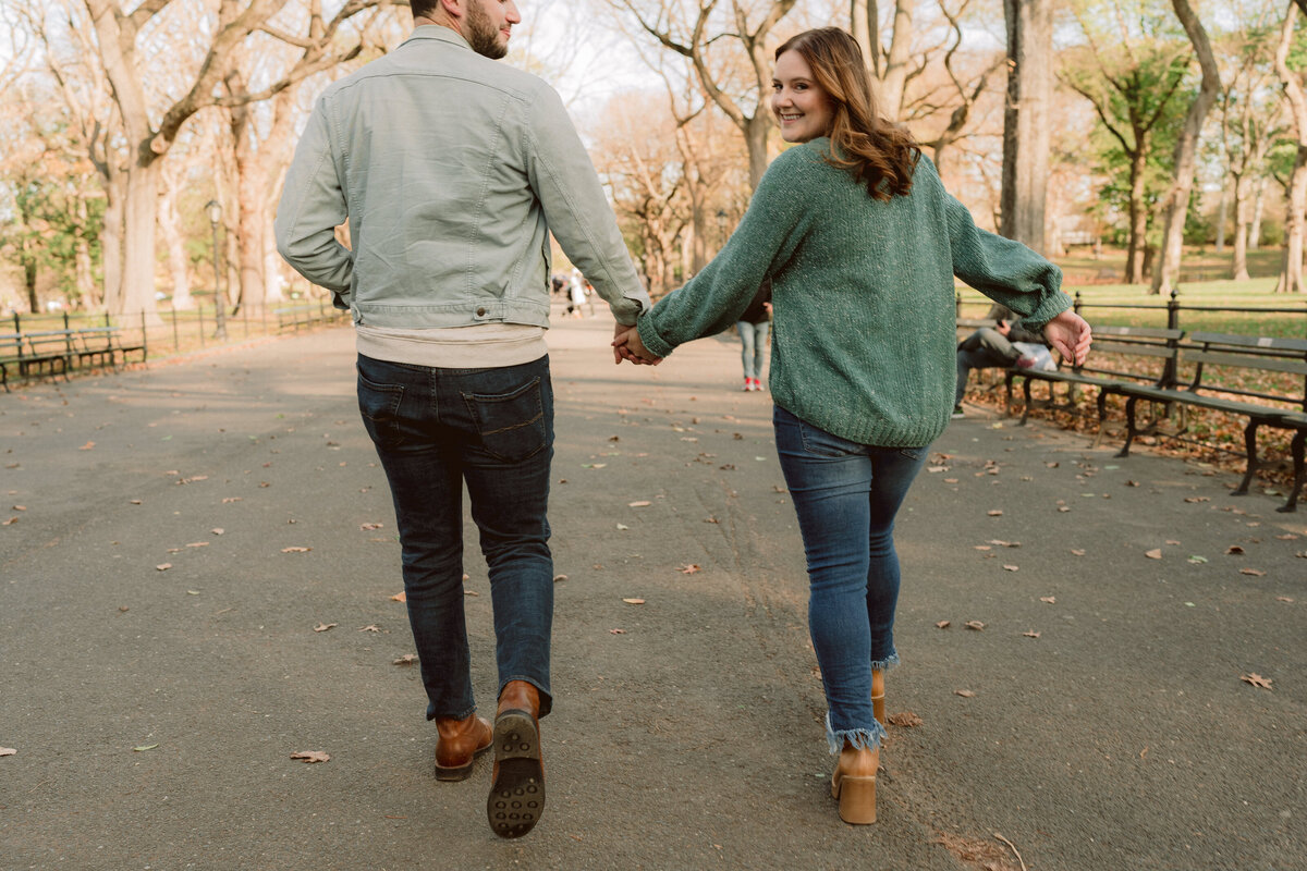 man and woman holding hands  and woman is smiling while looking over shoulder