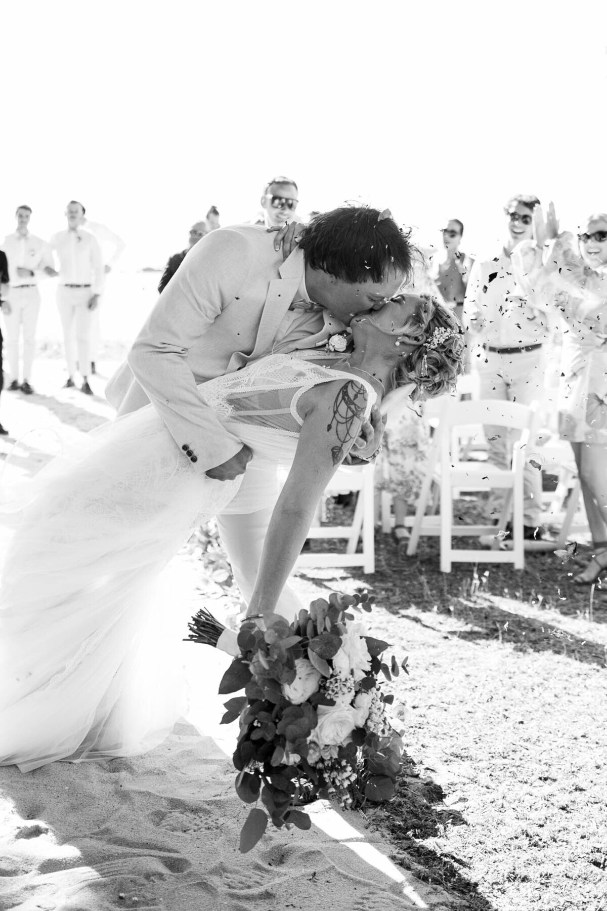 groom dips and kisses his new wife at the aisle.