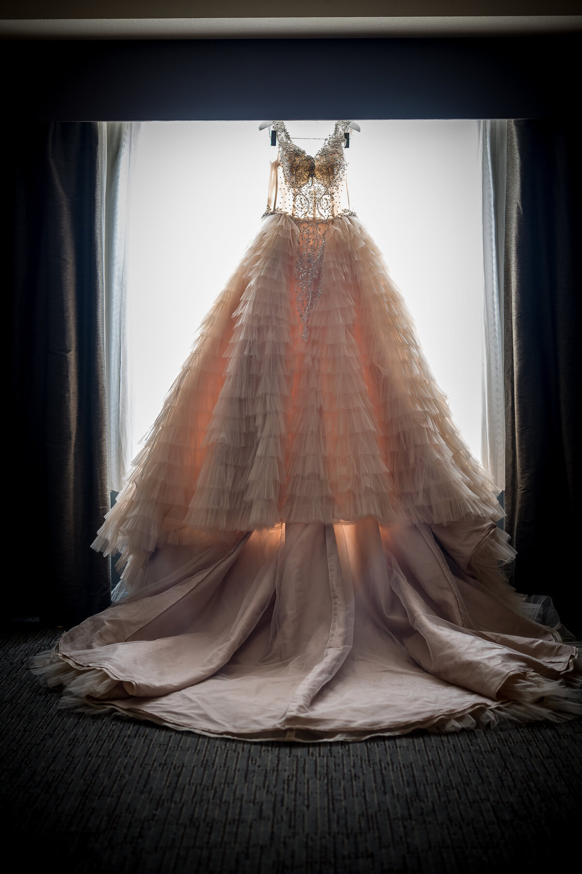 Lace wedding gown hanging with window light