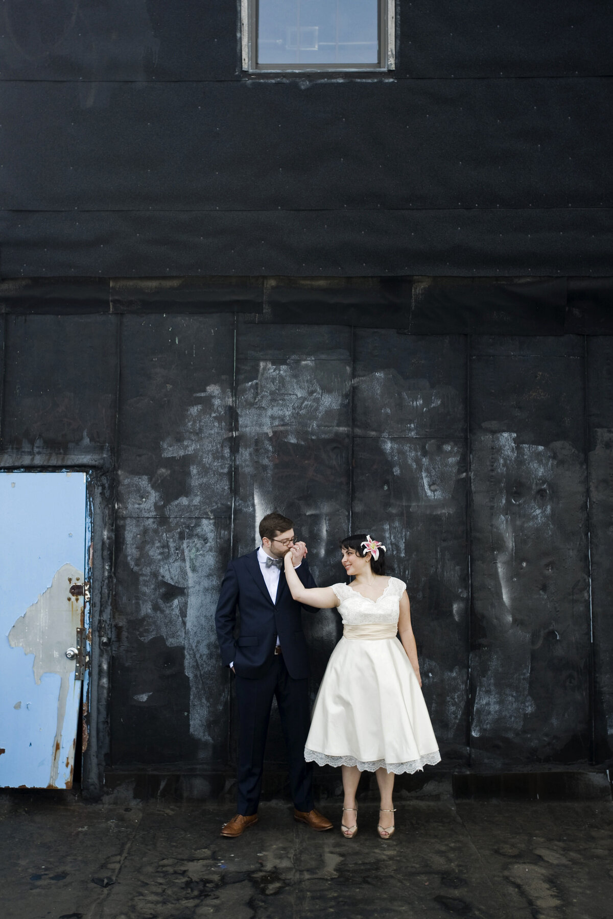 A newlywed holding their partner's hand and kissing it 