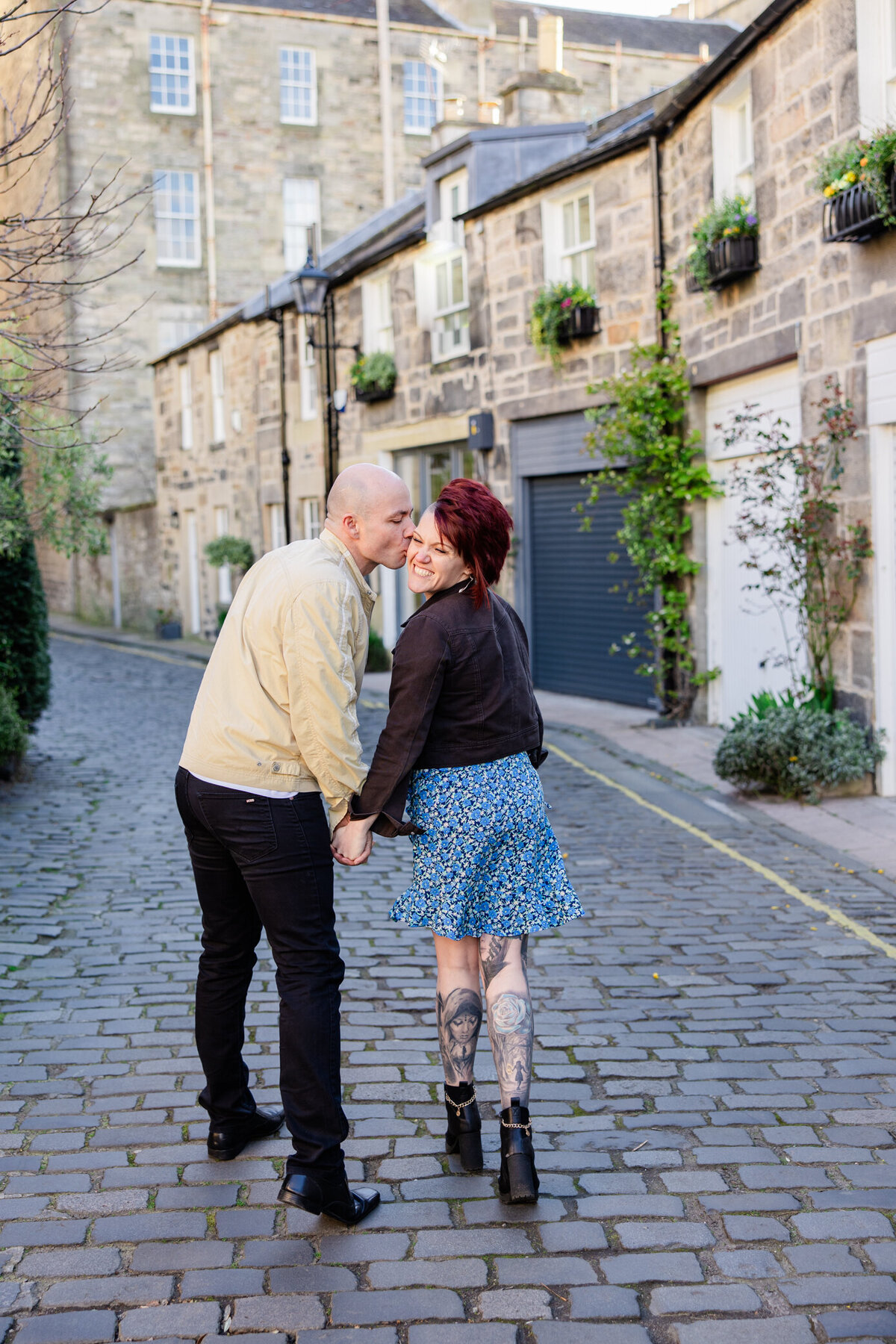 boy kisses girl on the cheek in circus lane, photo by Love is Magic Photo