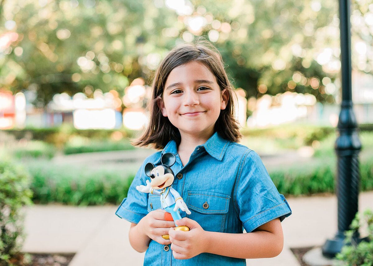 Little boy holding his Mickey Mouse toy and smiling