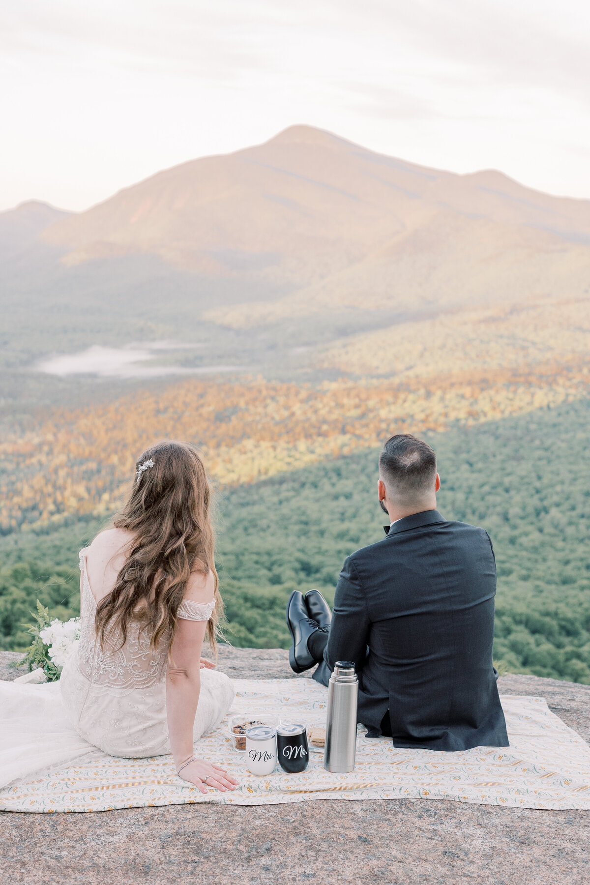 Bride and Groom watching the sunrise over the Adirondack Mountains while sharing a breakfast picnic on their wedding day.