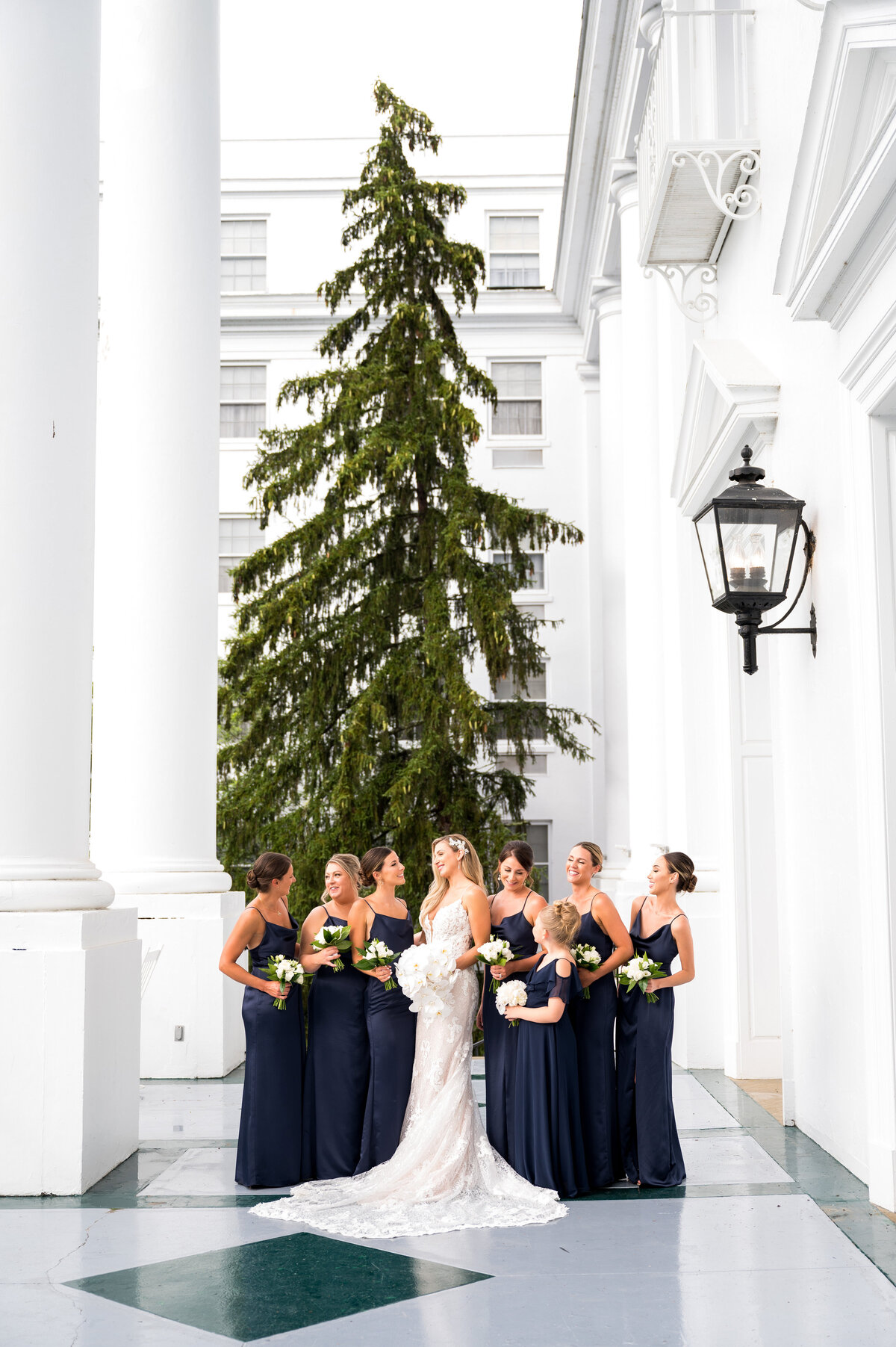bride and bridesmaids posing for wedding pictures on the column patio outside of the greenbrier resort