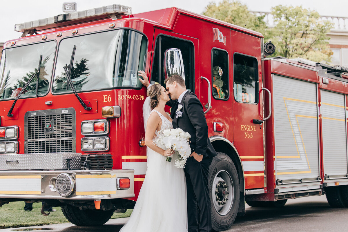 Bride and groom kissing in front of a red fire truck