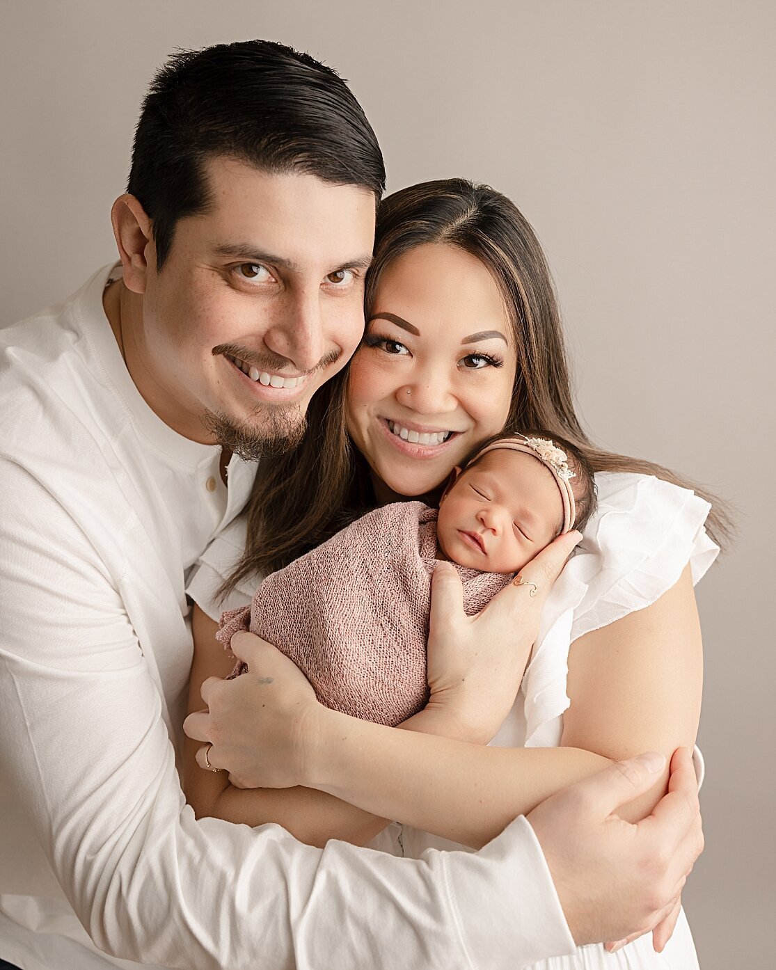 mom and dad smiling holding baby girl