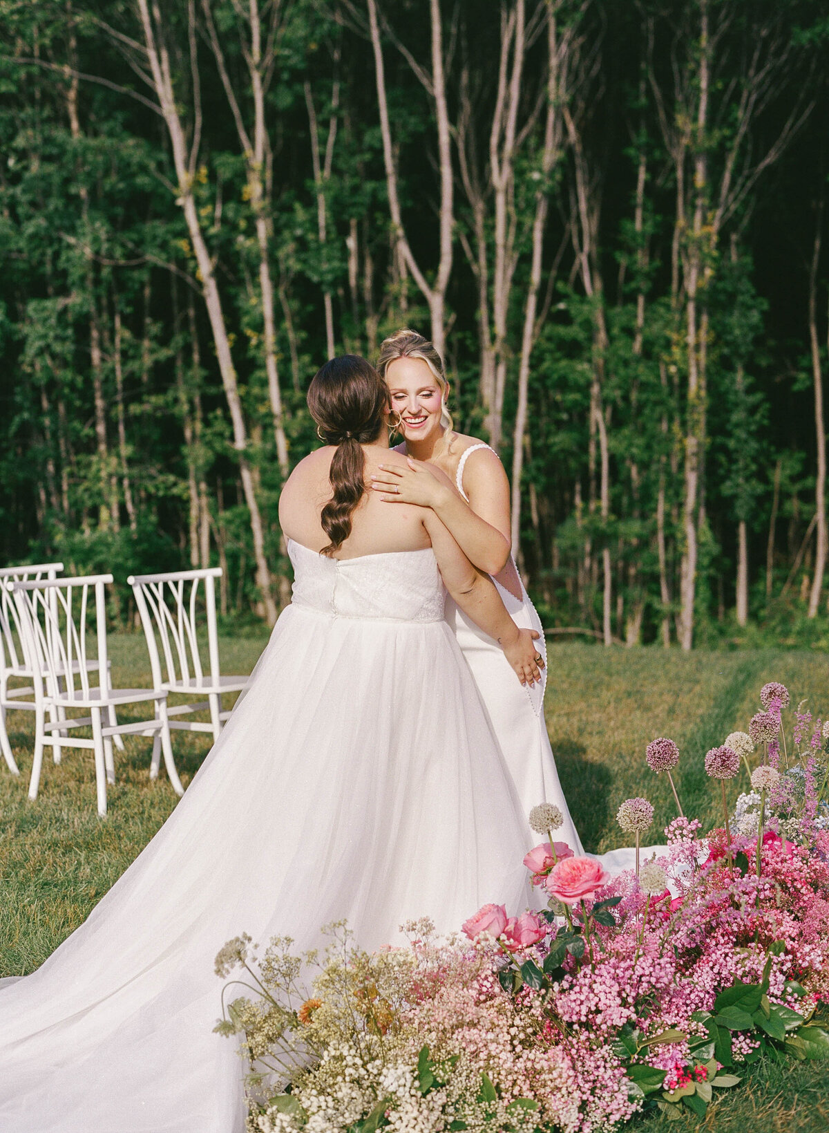 brides hug at altar in front of pink ceremony florals taken by boston documentary wedding photographer