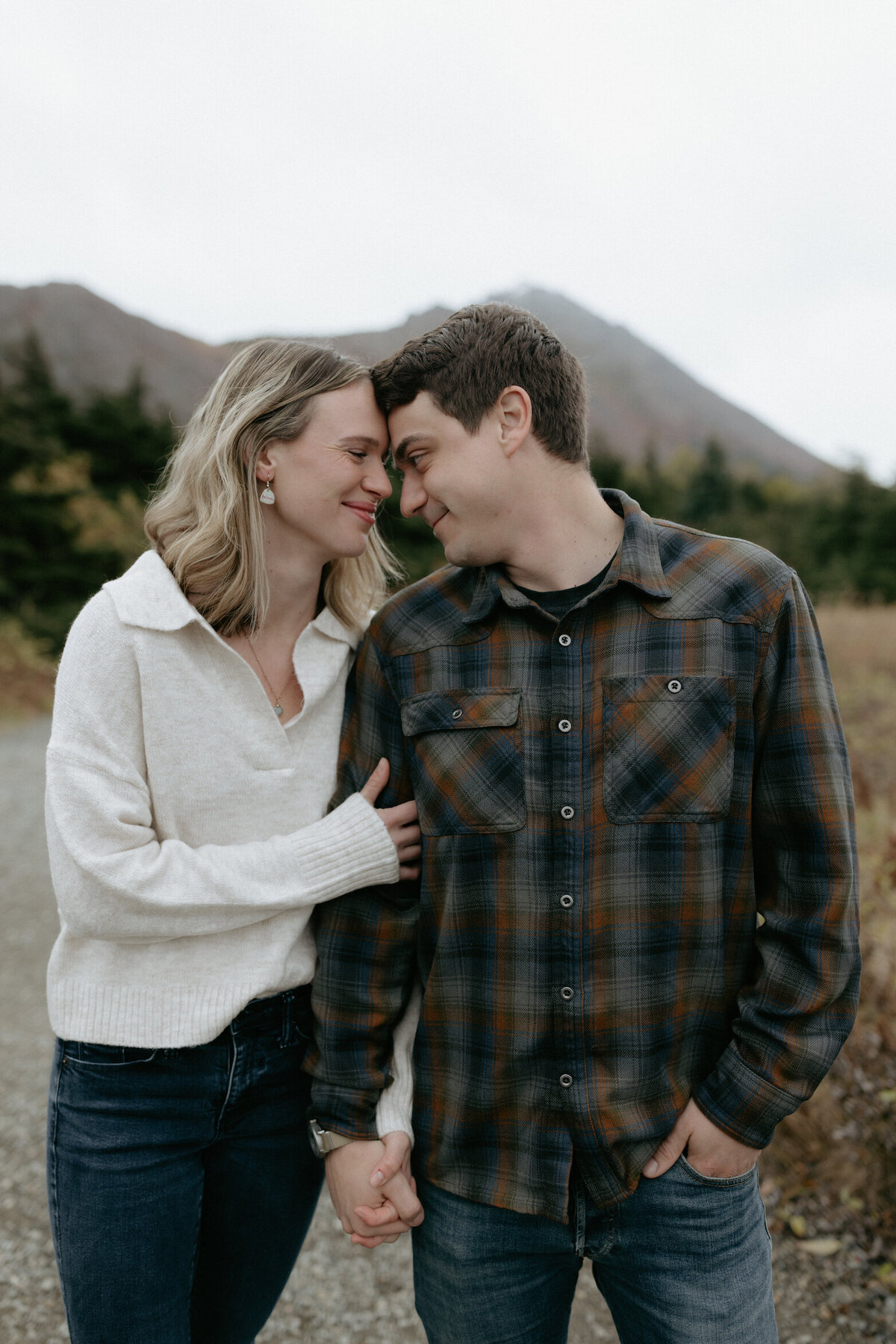 Couple snuggled up to one another near the mountains.