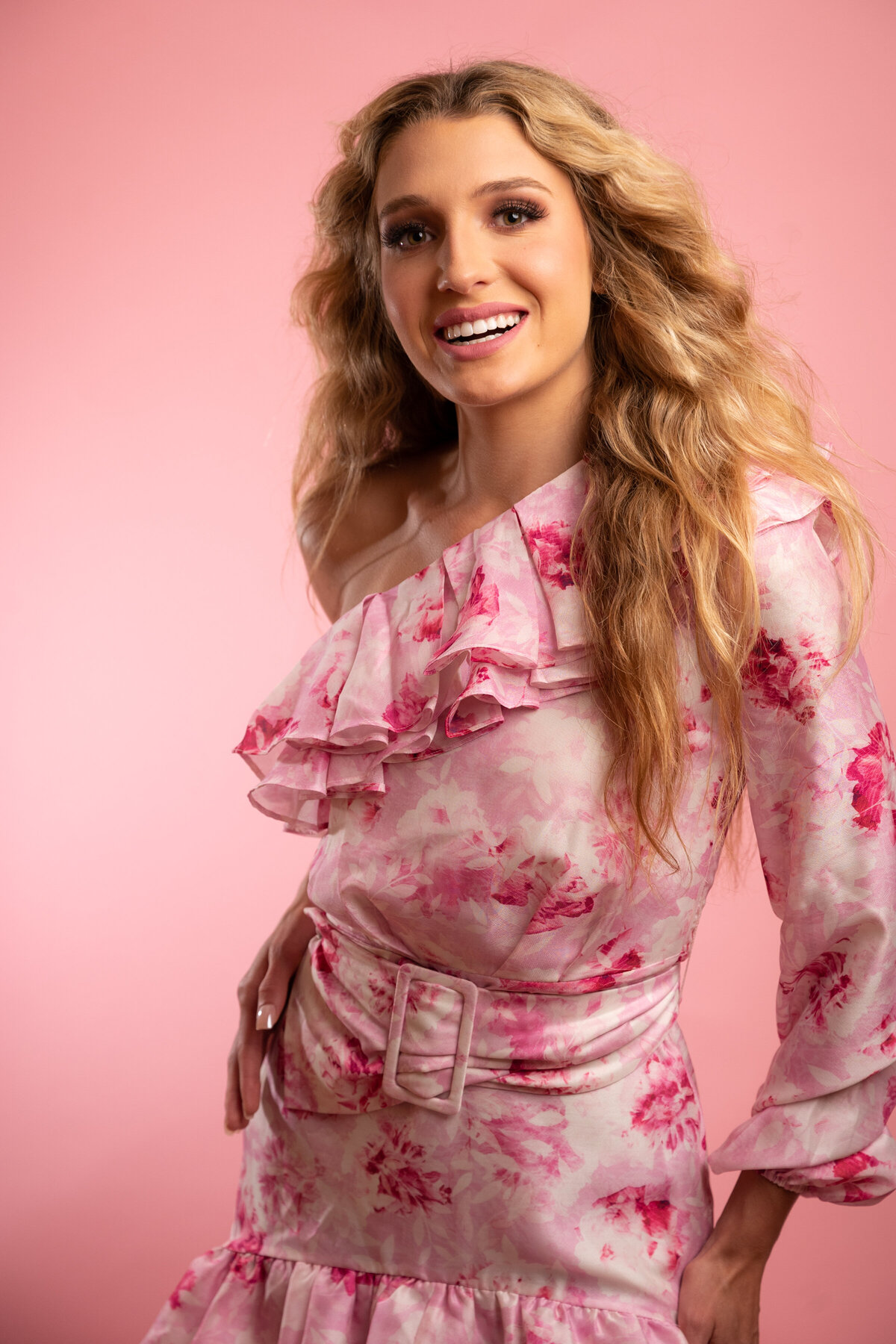 Close up of a blond  young woman wearing a pink flower dress in a pink backdrop