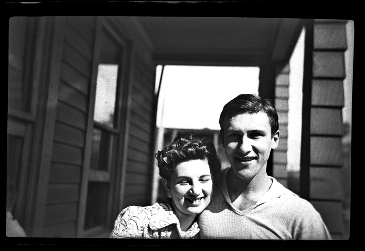 Black and white photograph of a couple looking at the camera smiling.