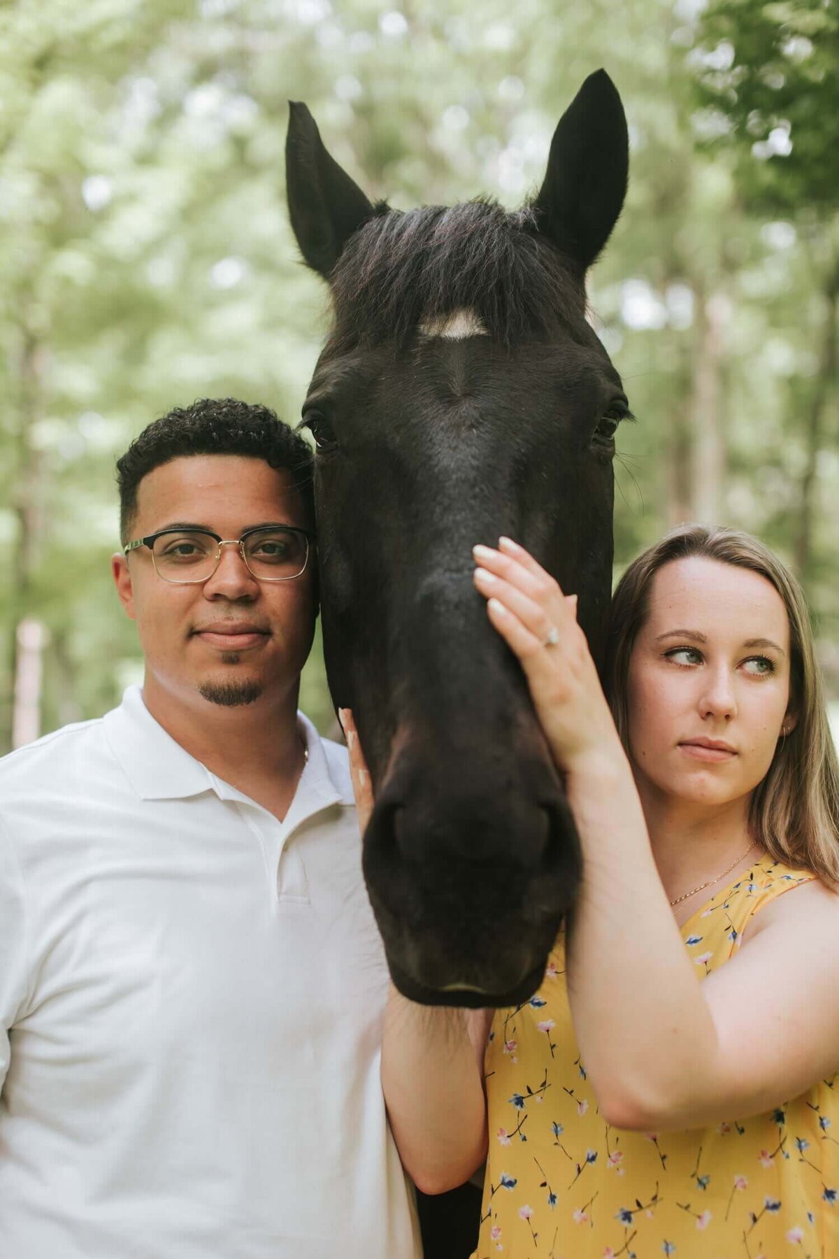 Couple standing on both sides of a horse surrounded by greenery in Upstate New York.