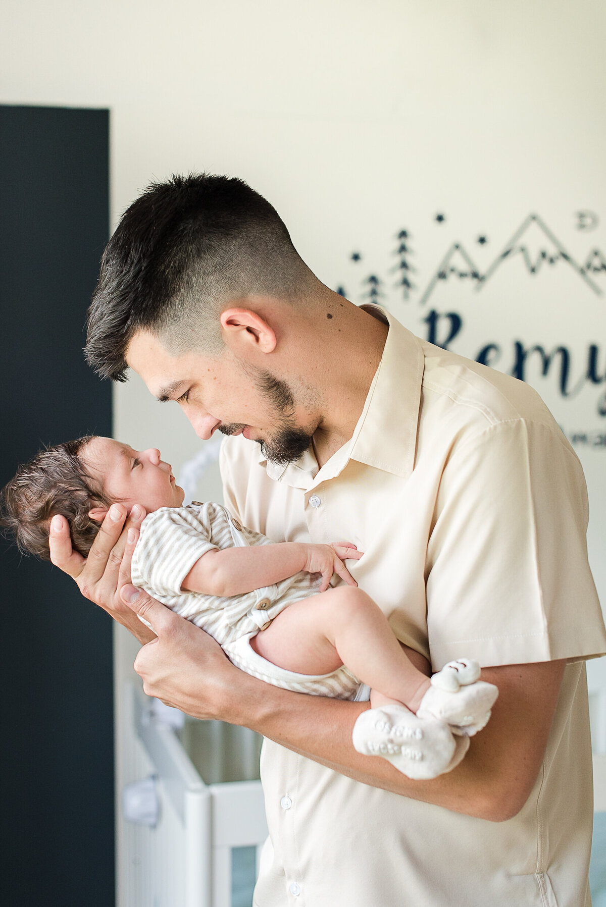 dad holding baby boy in neutral outfits in nursery